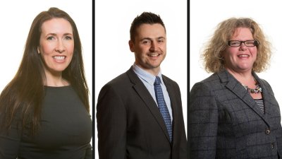 Three headshots in a row. On far left is a woman with long brown hair in a black long sleeve dress, in the middle is a man with short brown hair in a black suit jacket, light blue shirt and dark blue tie. On the right is a woman with a blonde, curly bob hairstyle, wearing dark, rectangular glasses and a grey blazer and blue and white striped top underneath