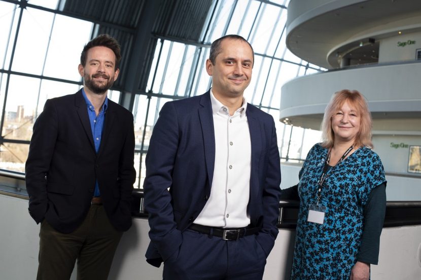 three people, smartly dressed, stand at the railing overlooking the inside of the Sage Gateshead