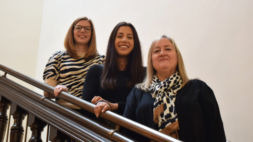 Three members of Convention Bureau team stood ascending staircase