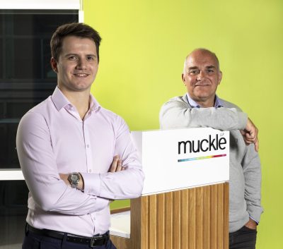 Two men stood in front of Muckle LLP podium