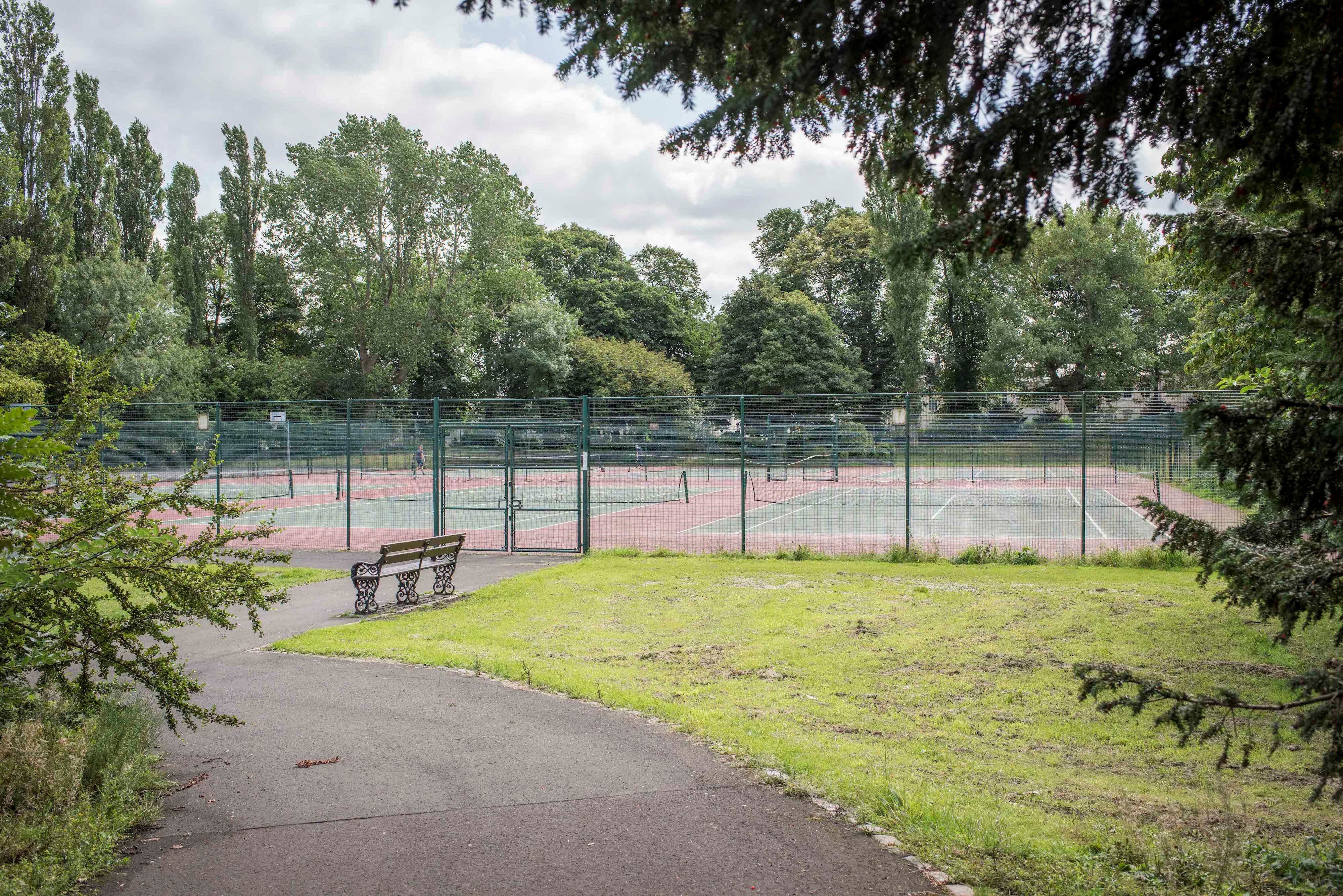 Public tennis courts in tree-lined park