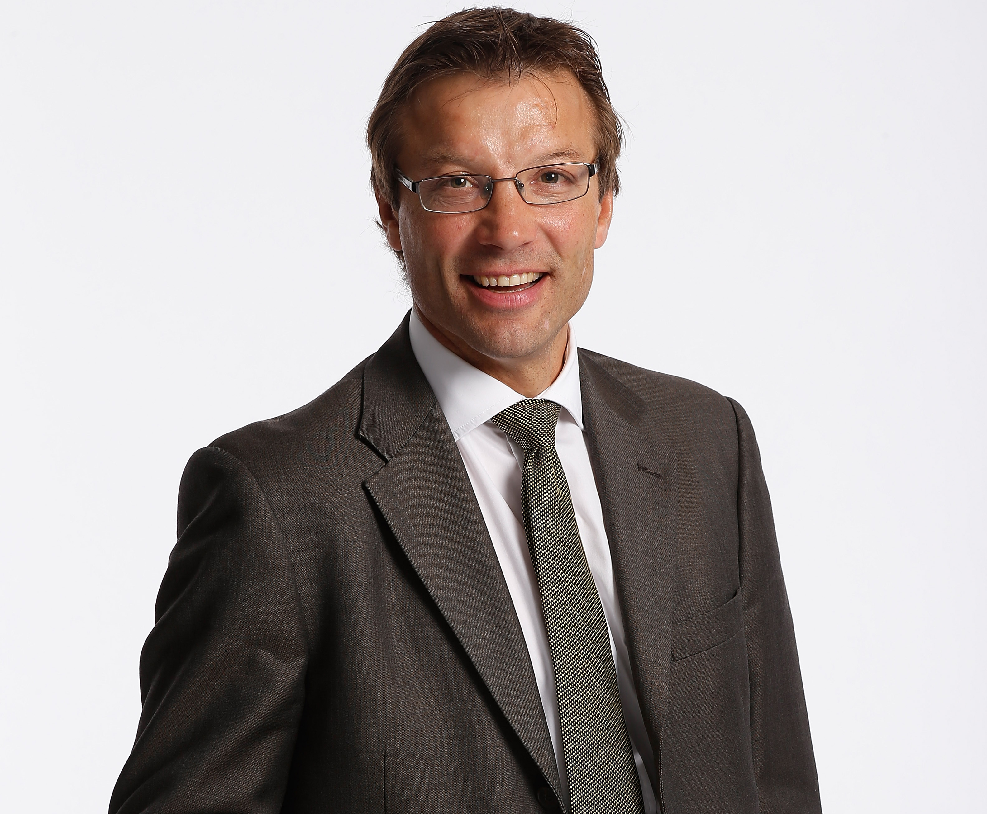 Headshot of Rob Andrew in suit and tie and wearing glasses.