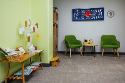 Image of the Mulit-faith Prayer Room at Newcastle Airport. The room has two green arm chairs, a table with children's books and a light green wall.