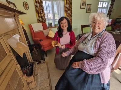 Head of Health and Wellbeing, Michelle Kindlysides toasting bread on an open coal fire with volunteer Ruth