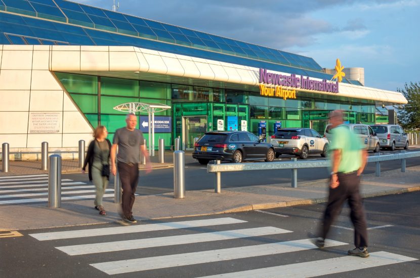 External of Newcastle Airport with people walking across street.