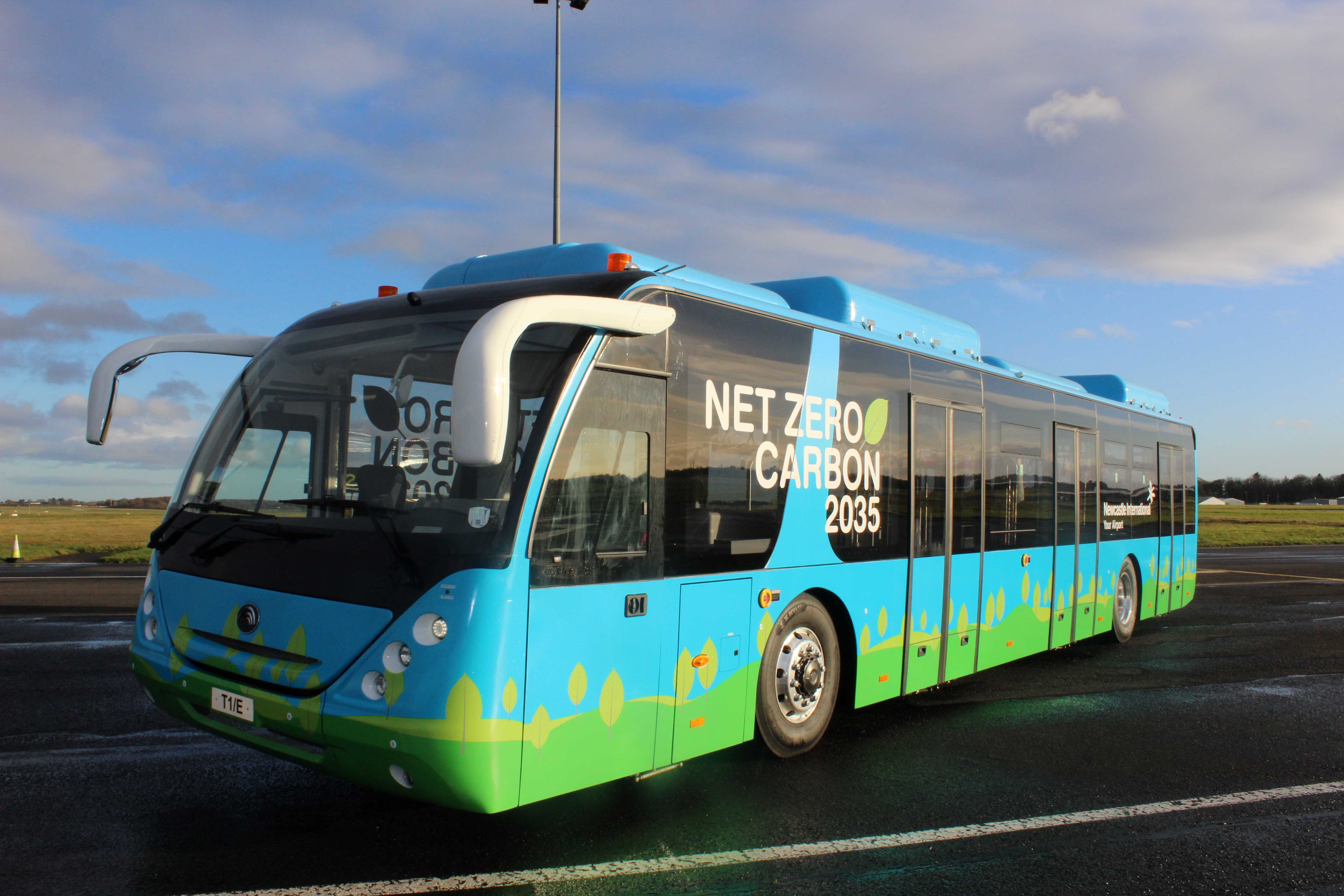 A blue and green electric bus on the airport tarmac