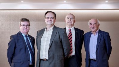 Group of four people from PulmoBioMed stood in front of bare wall smiling to camera