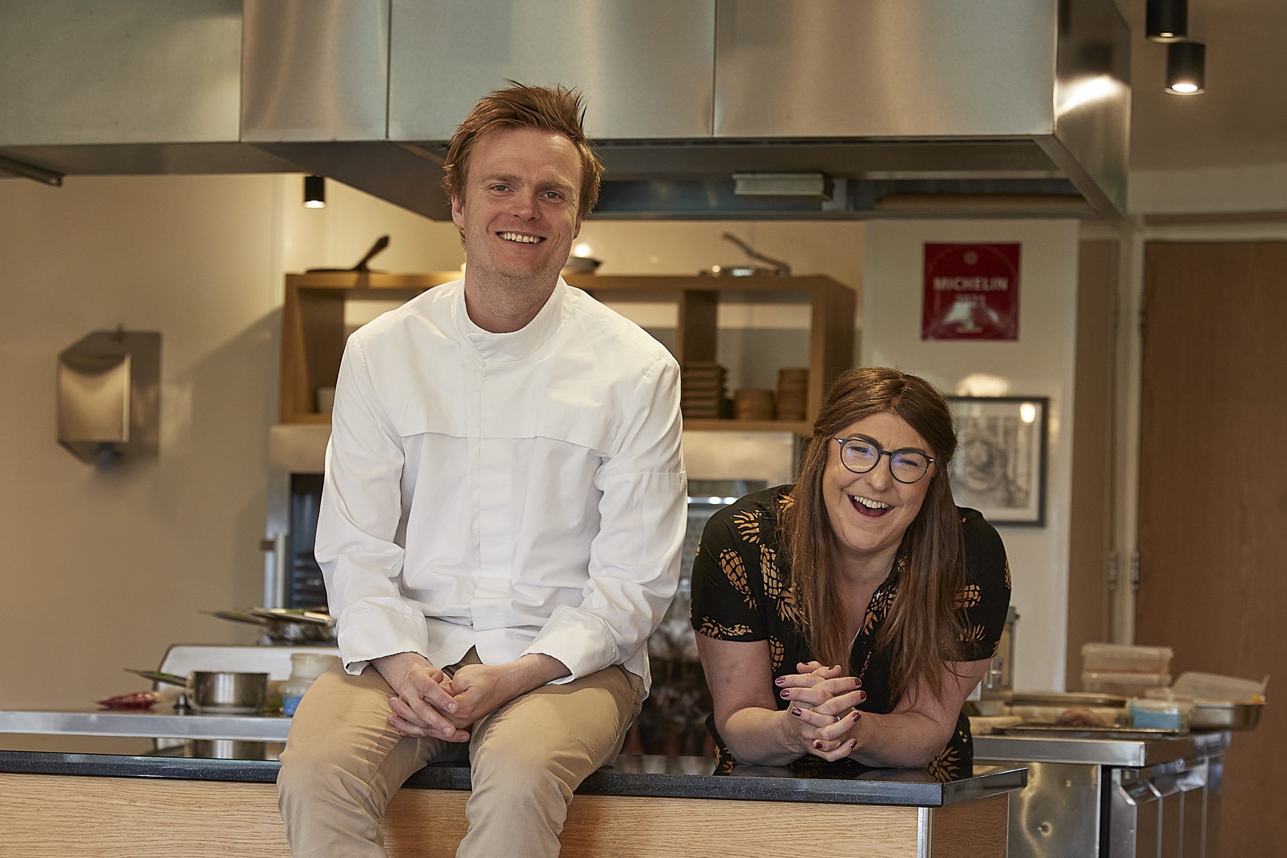 Hjem restaurant owners smiling to camera in a kitchen.