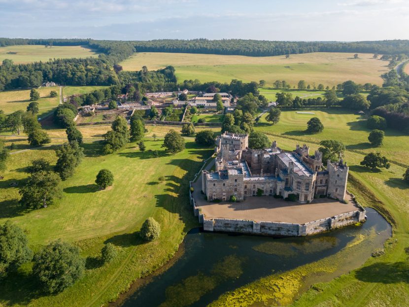 Aerial shot of Raby Estates including a castle keep surrounded by a moat and countryside fields spread into the distance.