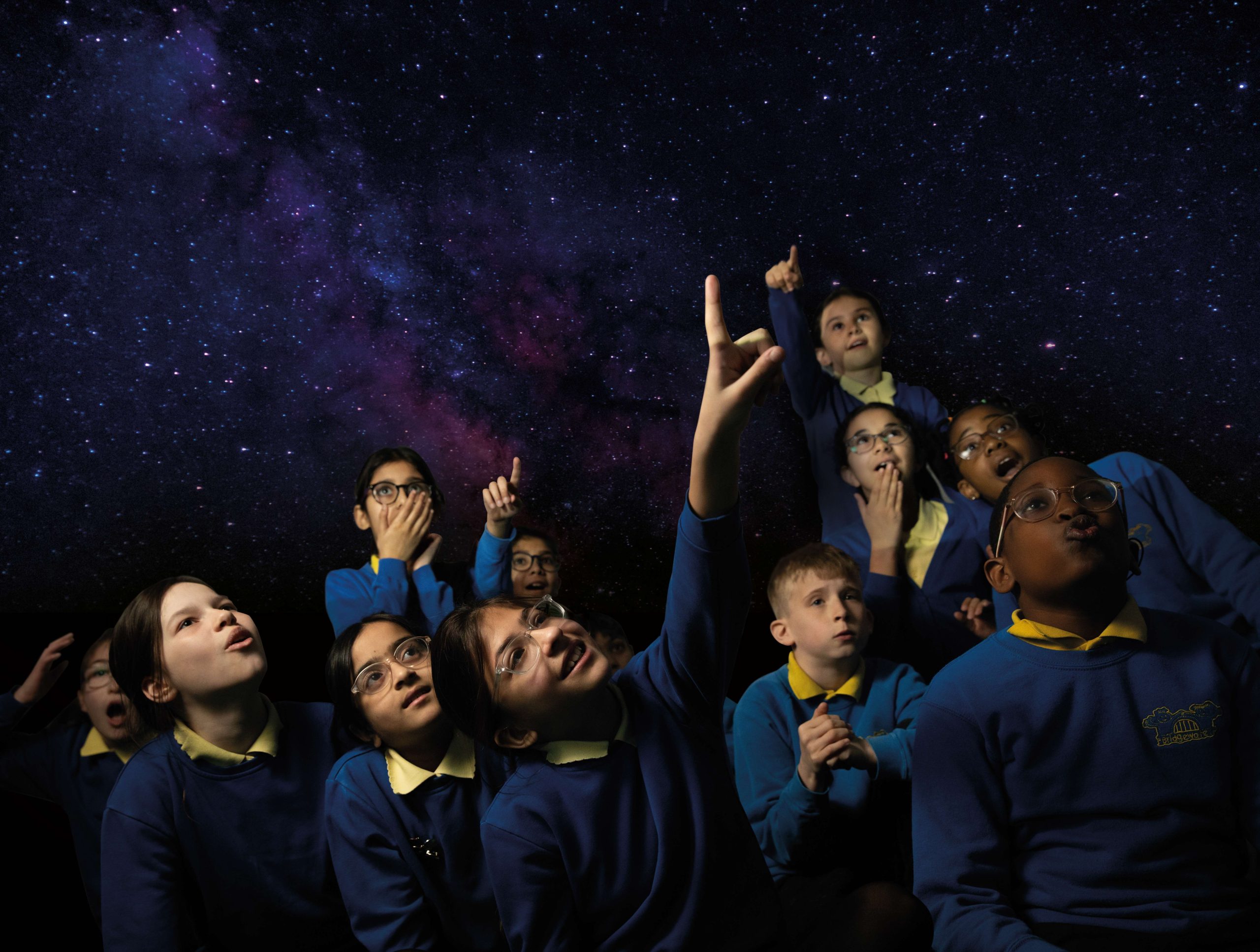 School children looking up at night sky in mobile planetarium