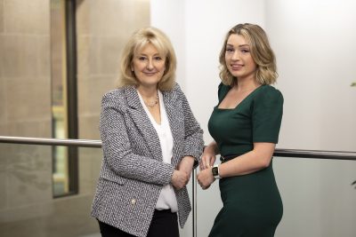 Susan Howe and Georgia Barber stood next to one another leaning against a banister