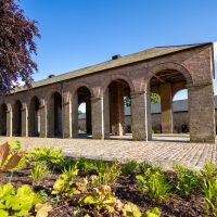 Dutch Barn building with rounded archways surrounded by gardens.