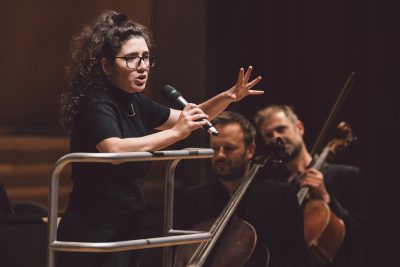 Nil Venditti speaking into a microphone to orchestra