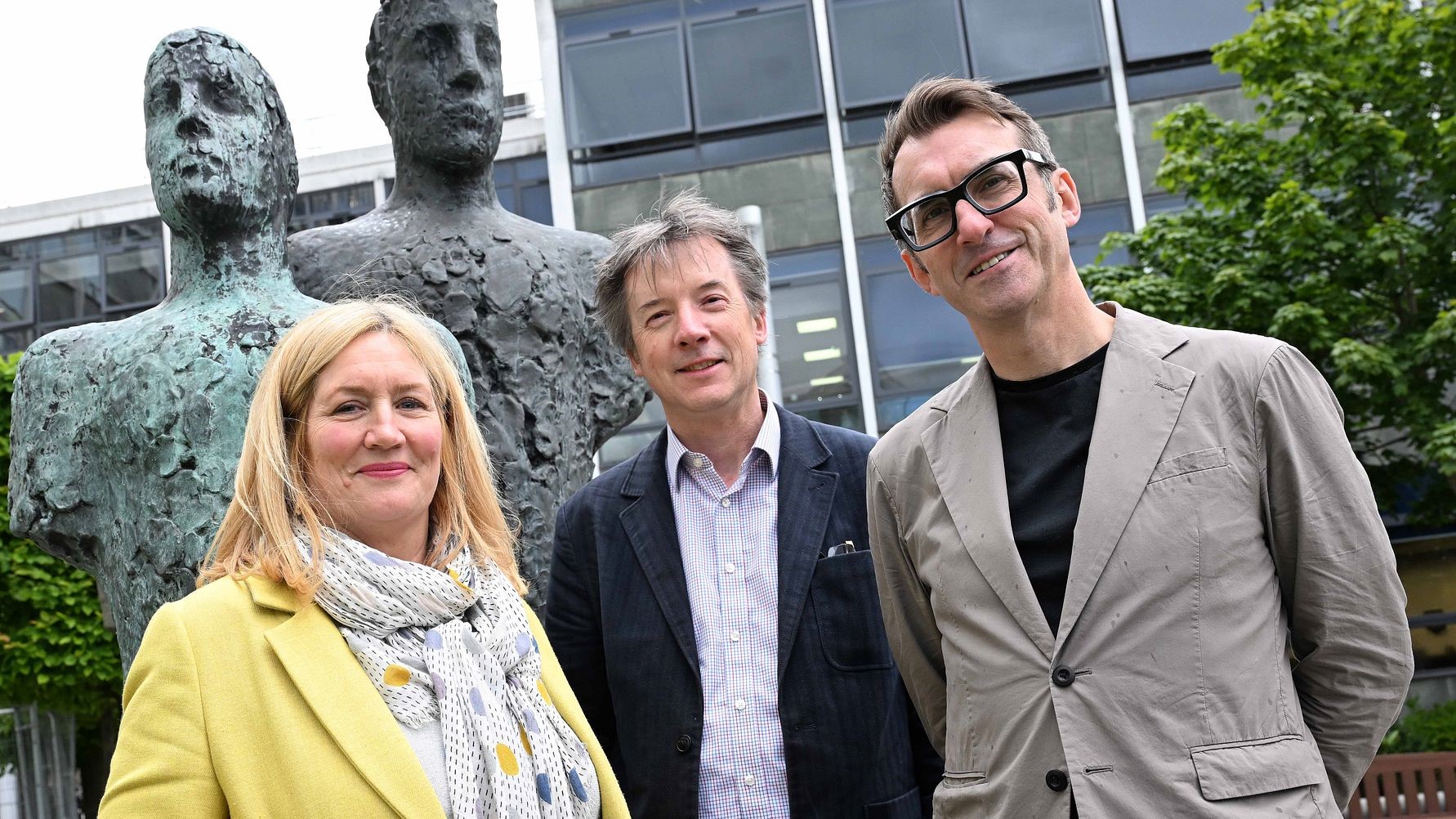 Jacqui Kell, Neil Percival and Keith Merrin standing outside smiling to camera with two large metal sculptures in the background.