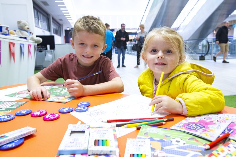 Two children sat at table colouring in.