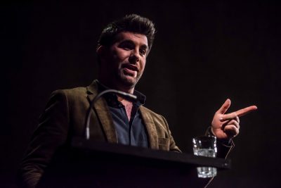 Person at a podium addressing an audience at a Ghost Stories lecture.