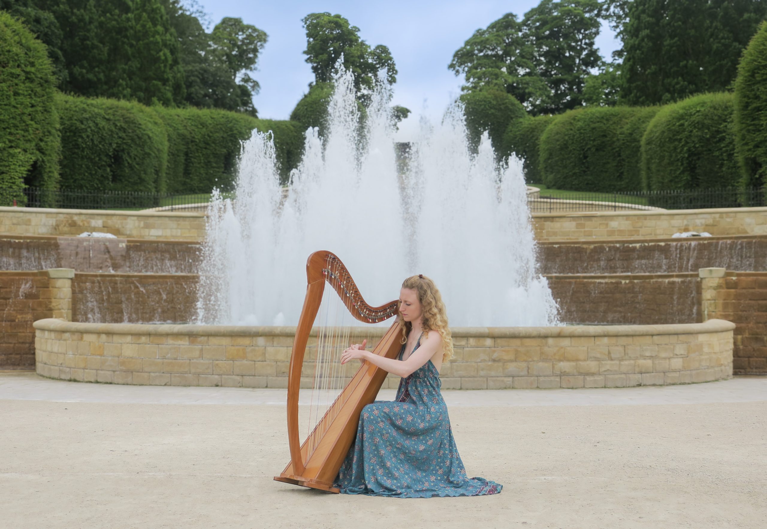 Harpist playing the harp in front of The Alnwick Gardens water fountain.