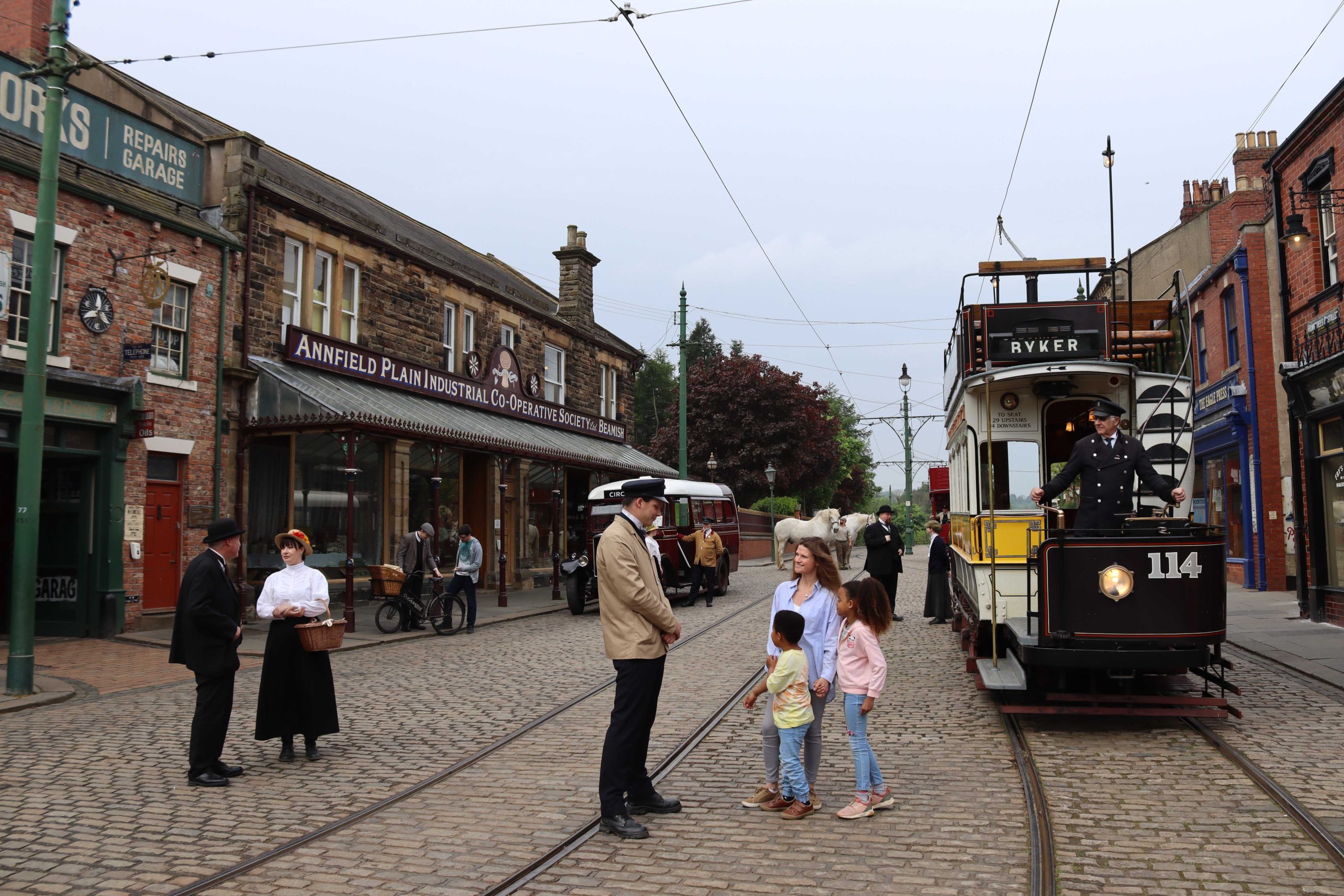 1900s-style town scene with tram and shops.