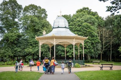 Pavilion in Exhibition Park with trees surrounding it and people walking through