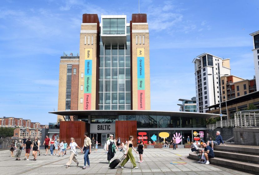 External shot of Baltic art gallery in the sunshine with lots of people milling around outside.