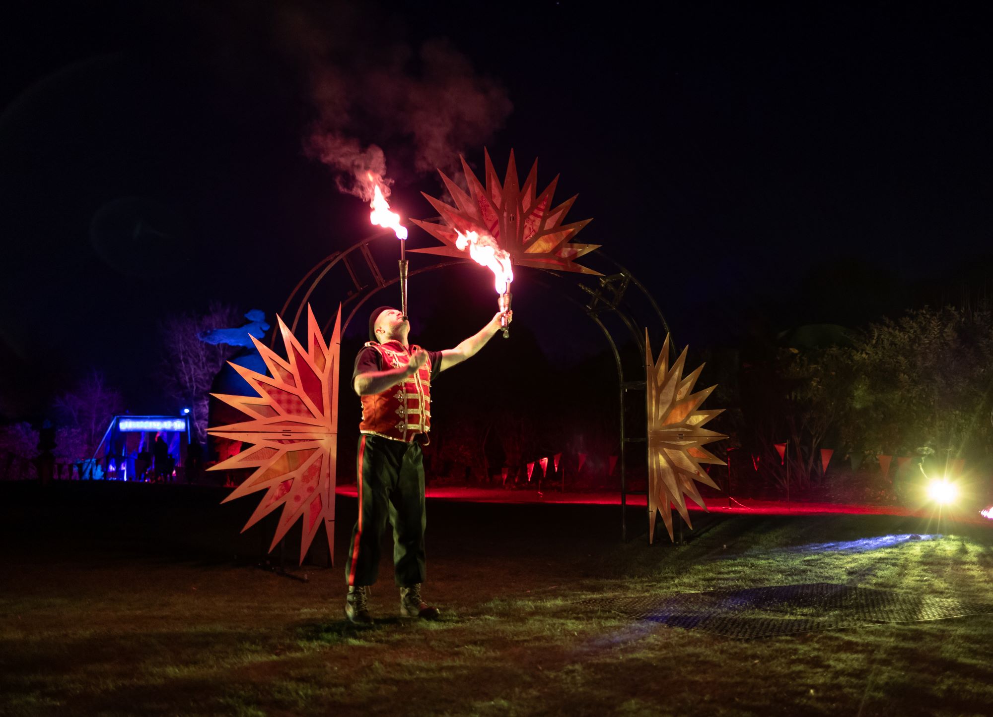 Fire breather performing in a field at night.