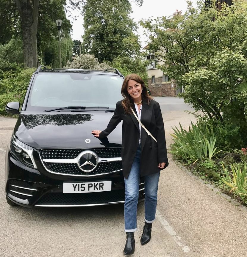 Davina McCall in front of a black Mercedes chauffeur car.