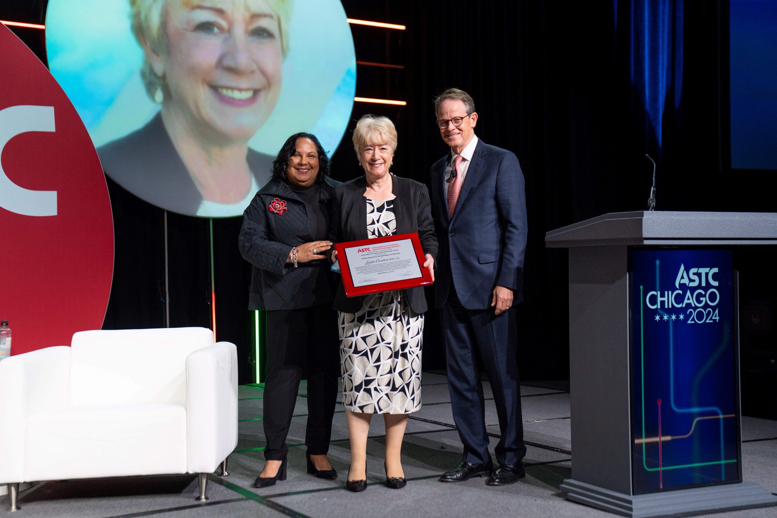 Linda accepting award on-stage in Chicago with two people stood on either side of her.