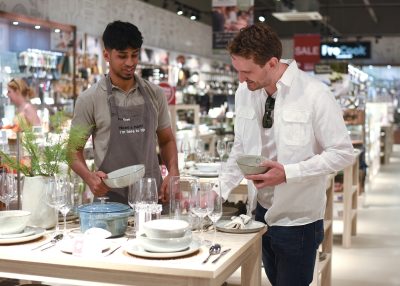 Shop worker talking to customer over crockery.