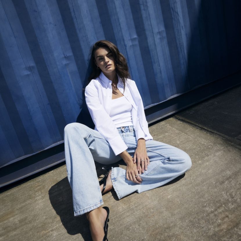 River Island model slouched against a wall in casual position.