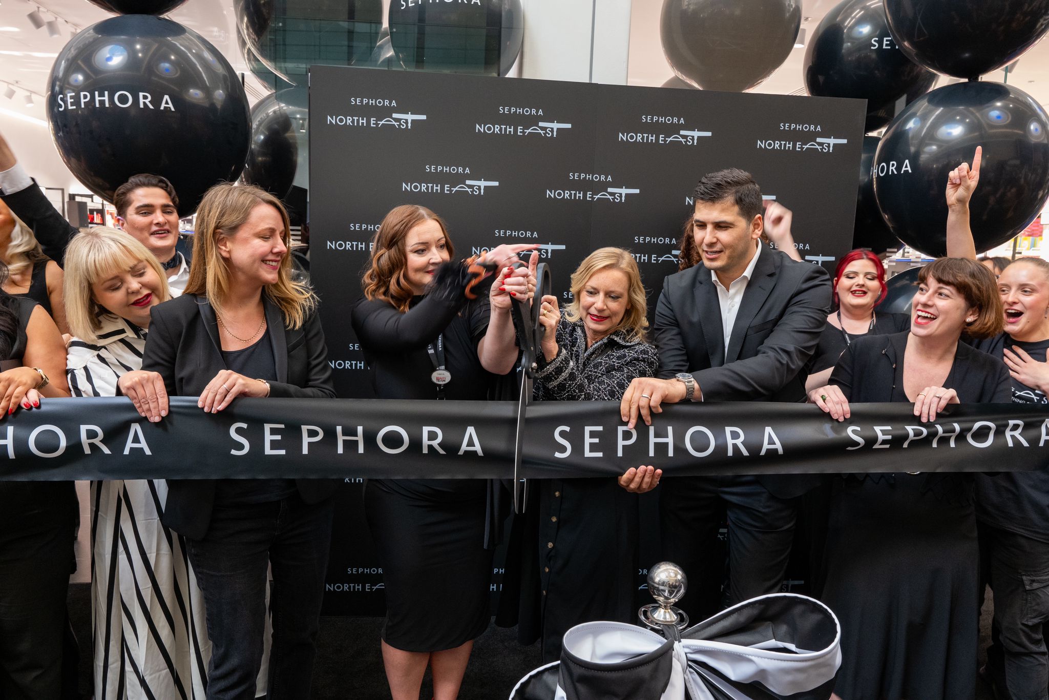 Group of people cutting a Sephora ribbon with giant scissors