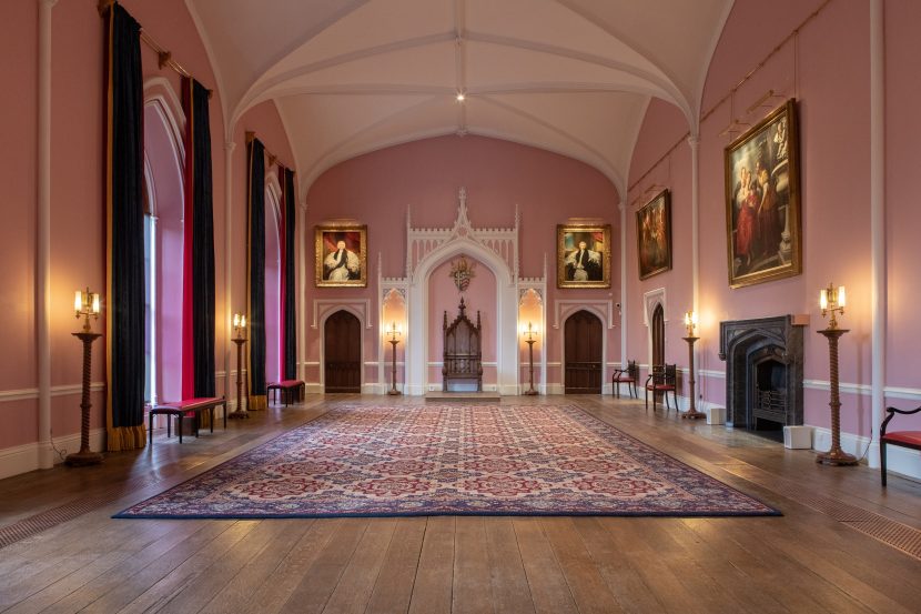 Grand pink room with a throne at the top in the middle.