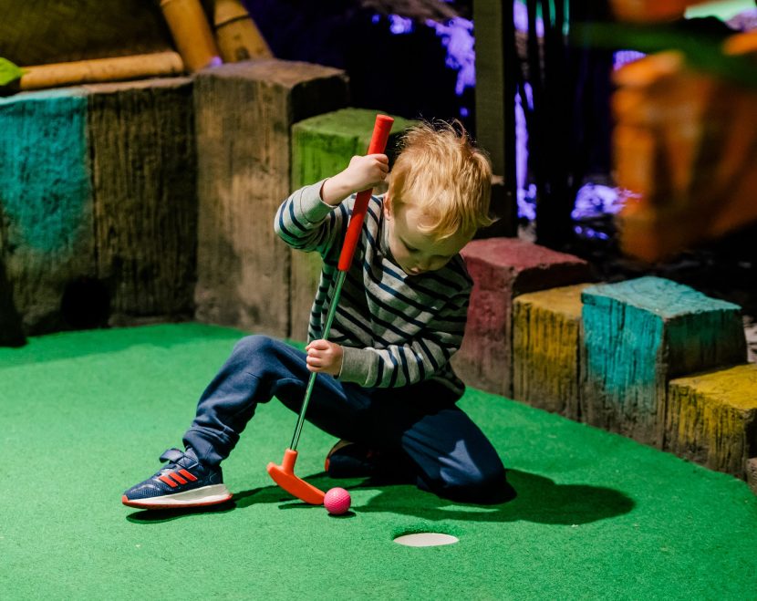 Child playing mini golf.