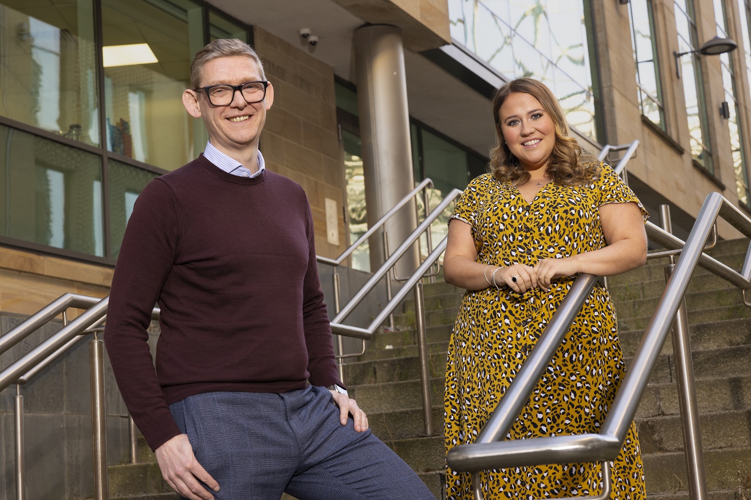 Anthony and Lucy on steps outside of Muckle LLP offices smiling to camera