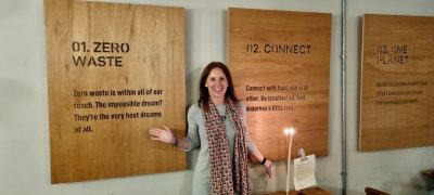 Sarah Thackray in front of three wooden boards on a wall