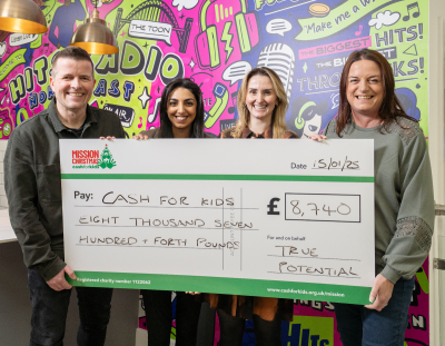 Four people stood holding a large cheque for Mission Christmas